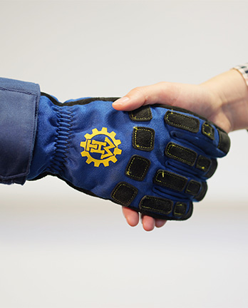 Zwei Personen geben sich die Hände, eine Hand steckt dabei in einem blauen THW-Handschuh.