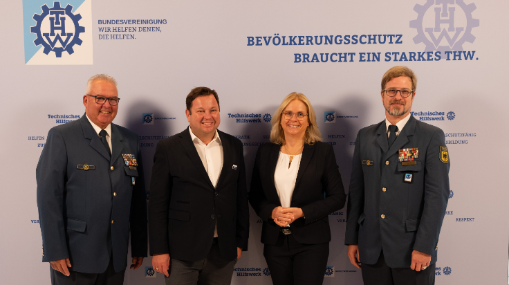 Vier Personen stehen lächelnd vor einer weißen Wand mit den Schriftzügen der THW-Bundesvereinigung sowie dem Logo des Technischen Hilfswerks. (Quelle: THW/Michael Walsdorf) Vier Personen stehen lächelnd vor einer weißen Wand mit den Schriftzügen der THW-Bundesvereinigung sowie dem Logo des Technischen Hilfswerks.