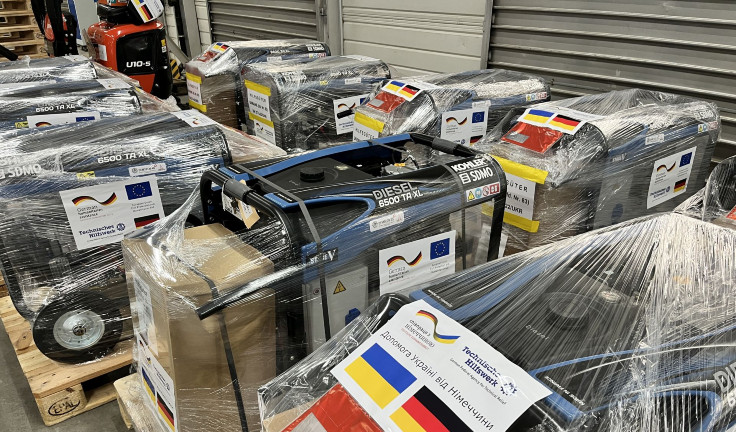 Acht Stromerzeuger stehen in zwei Reihen in Plastikfolie eingepackt auf Paletten. Darauf befinden sich Aufkleber mit einer deutschen und einer ukrainischen Flagge sowie dem Logo des Technischen Hilfswerks. (Quelle: THW) Acht Stromerzeuger stehen in zwei Reihen in Plastikfolie eingepackt auf Paletten. Darauf befinden sich Aufkleber mit einer deutschen und einer ukrainischen Flagge sowie dem Logo des Technischen Hilfswerks.
