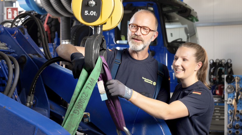 Two people in THW clothing are standing at a machine. (Source: THW) Two people in THW clothing are standing at a machine.