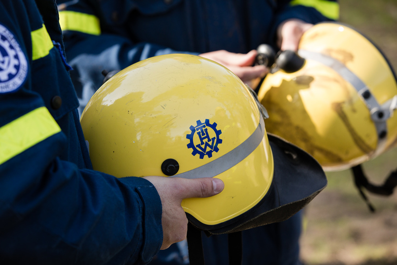 One hand is holding a yellow THW helmet. In the background there are also hands holding another THW helmet. (Source: THW) One hand is holding a yellow THW helmet. In the background there are also hands holding another THW helmet.