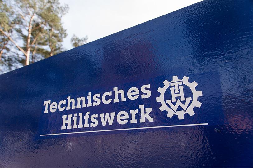 The logo of the Federal Agency for Technical Relief is depicted on a blue, metallic surface. (Source: THW) The logo of the Federal Agency for Technical Relief is depicted on a blue, metallic surface.
